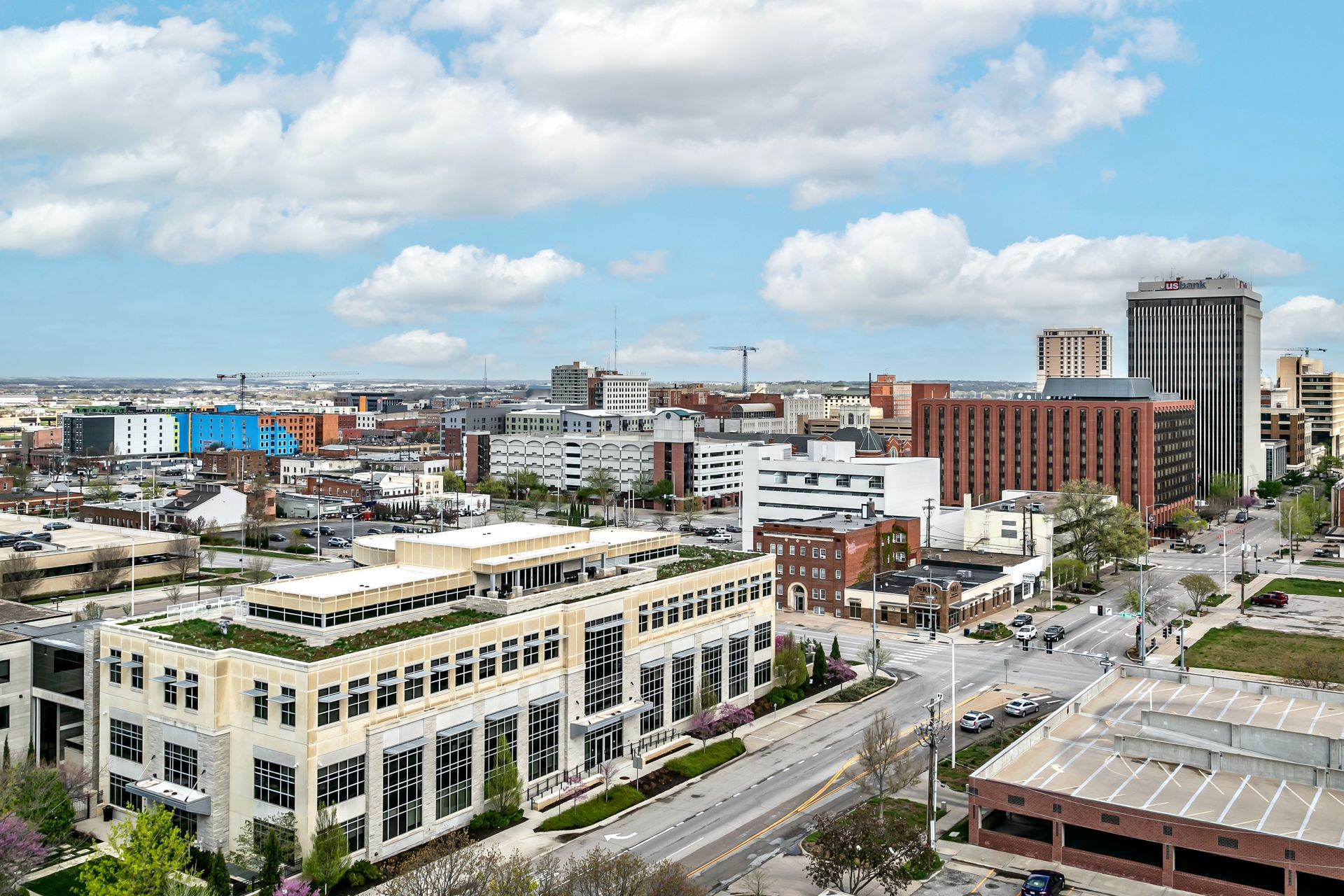 Downtown cityscape with modern buildings, streets, and a blue sky with clouds