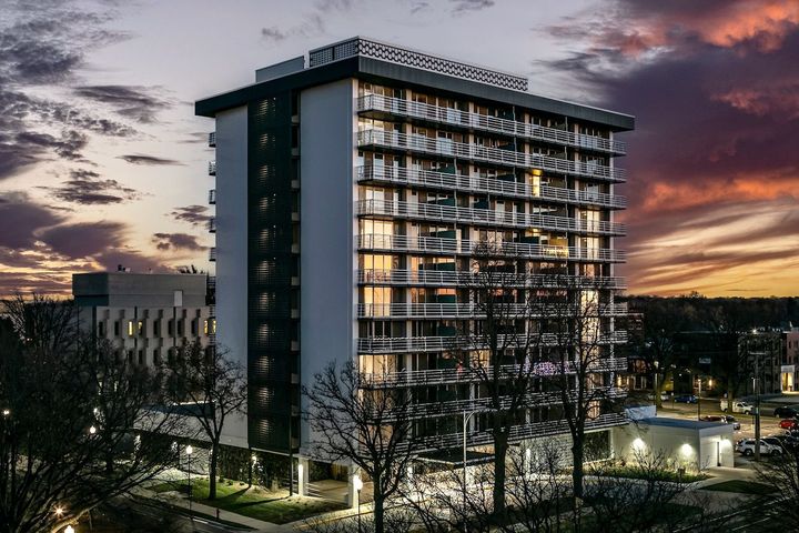 Modern glass office building at dusk with illuminated windows and a colorful sunset sky