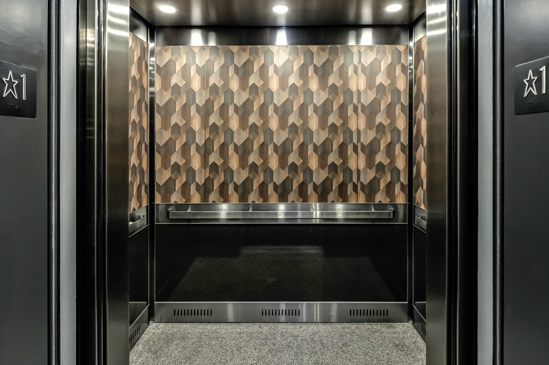 Empty elevator interior with patterned wall paneling and metallic doors
