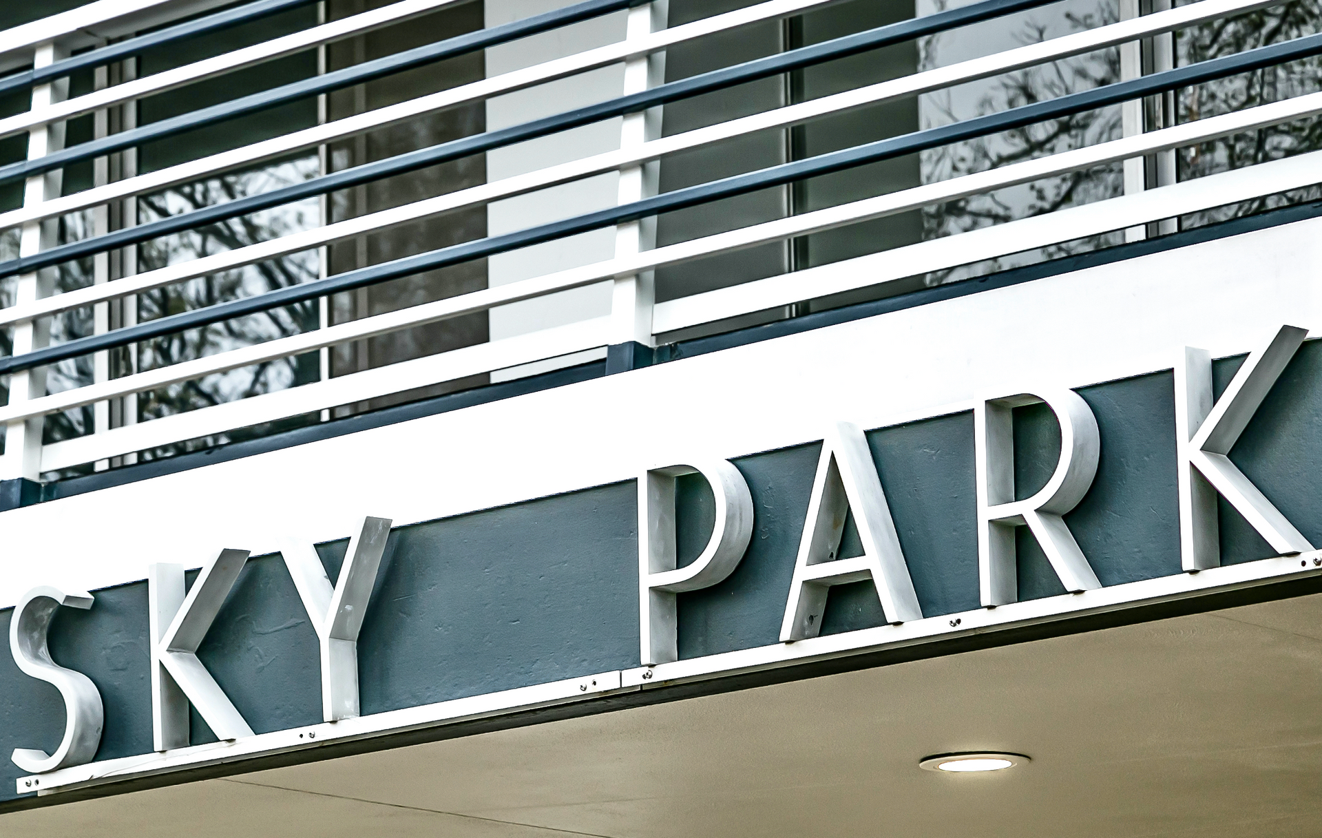 Sign reading “SKY PARK” on a building facade with metal railings above.