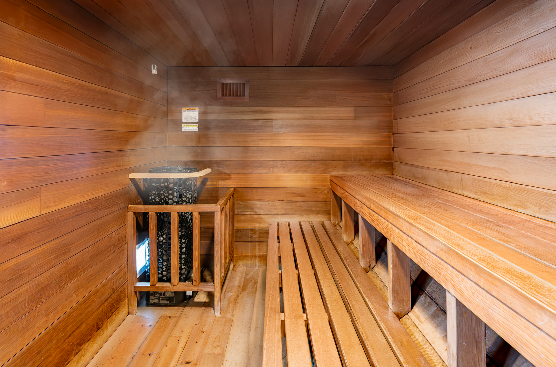 Wood-paneled sauna with wooden benches and a heater stove on the left