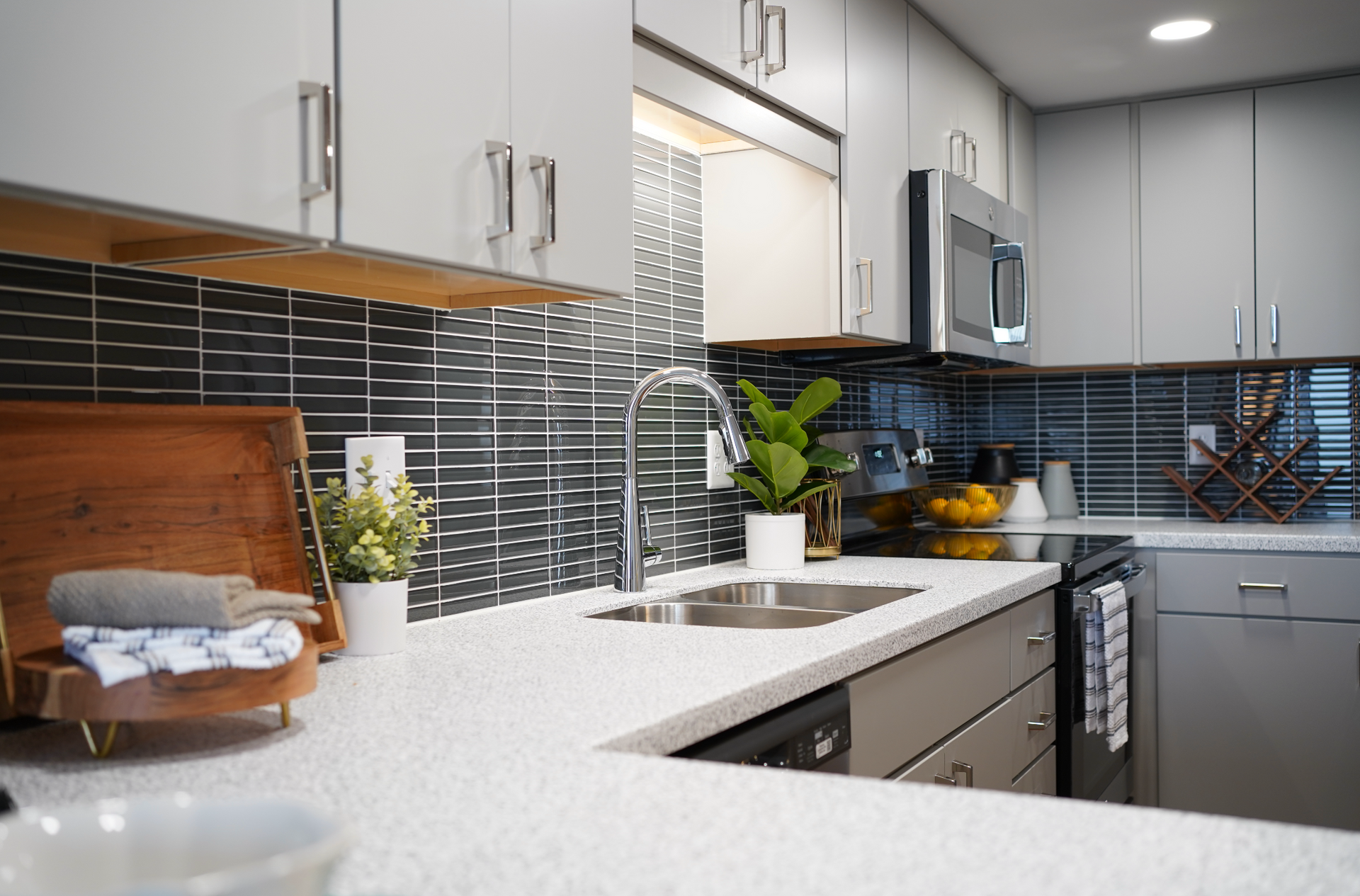 Modern kitchen with white cabinets, gray tile backsplash, granite countertops, and a sink by the window