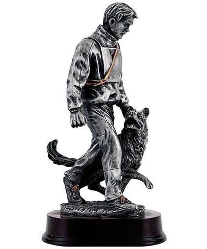 Een jongen loopt naast een standbeeld van een zwarte hond op een ronde sokkel.