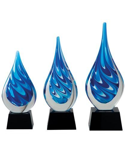 Drie blauwe, vlamvormige glazen awards op zwarte sokkels, gerangschikt van kortst naar langst.