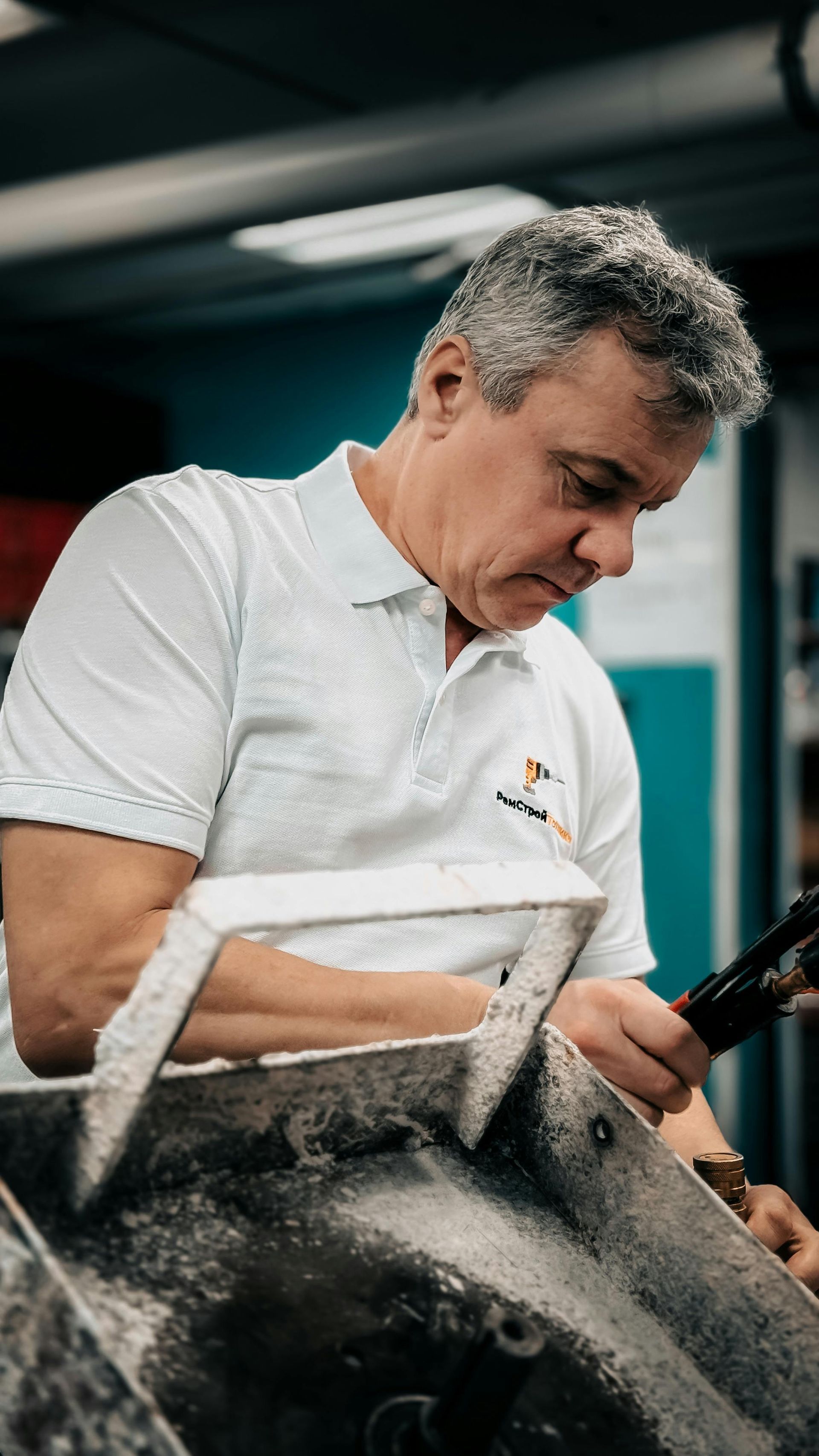 Een monteur in een wit shirt inspecteert een grote band in een werkplaats.