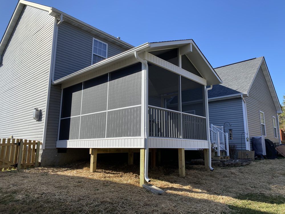 A screened in porch is sitting in the backyard of a house.