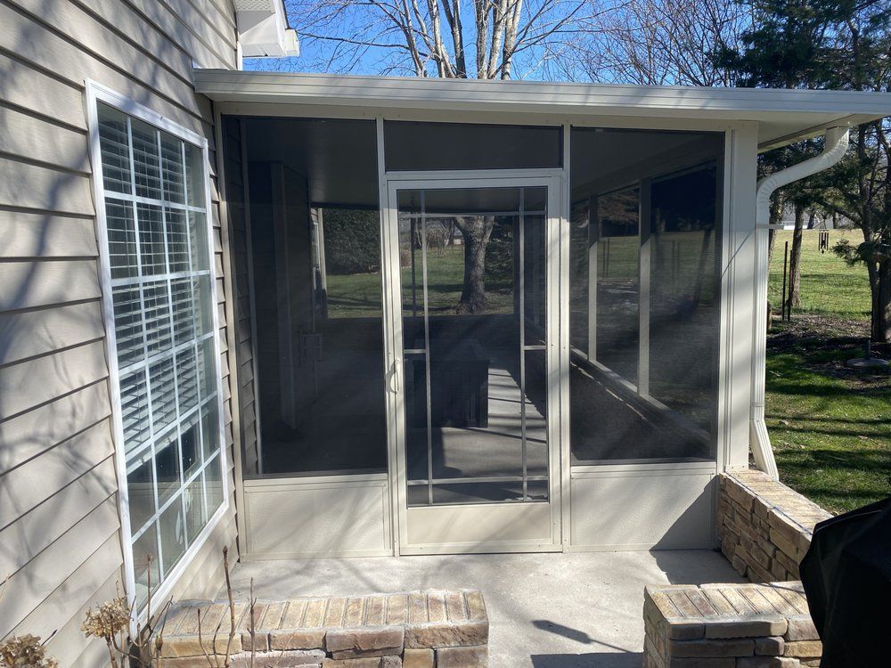 A screened in porch with a grill in the backyard of a house.