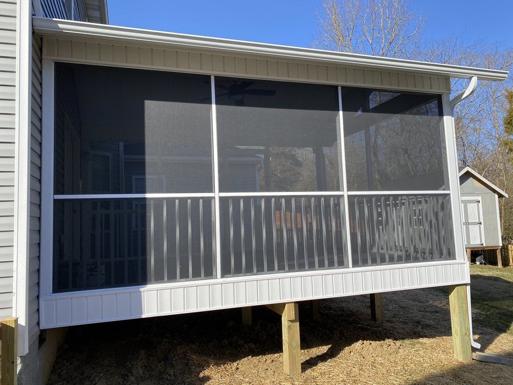 A screened in porch with a white house in the background.