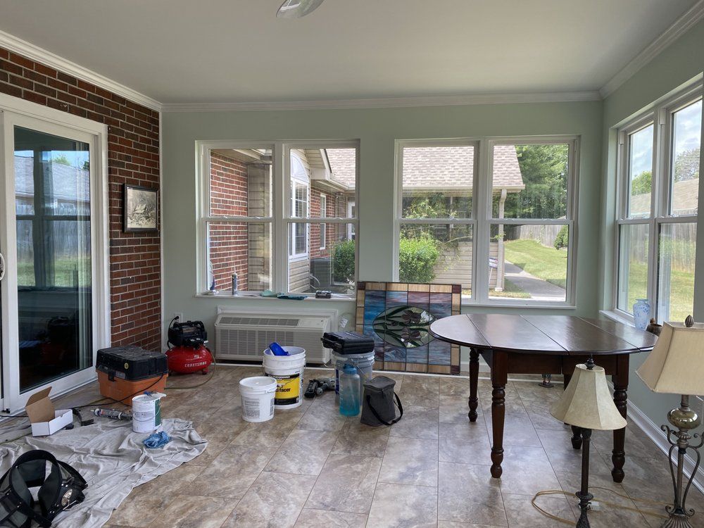 A room with a table and a lot of windows is being painted.