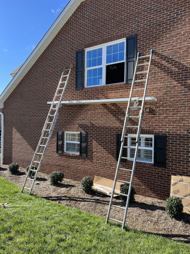 A ladder is sitting on the side of a brick building next to a window.