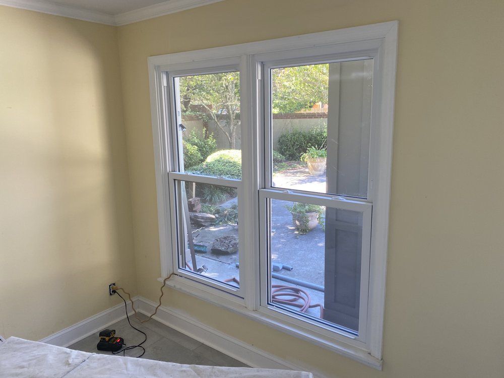 A room with two windows and a hose on the floor.