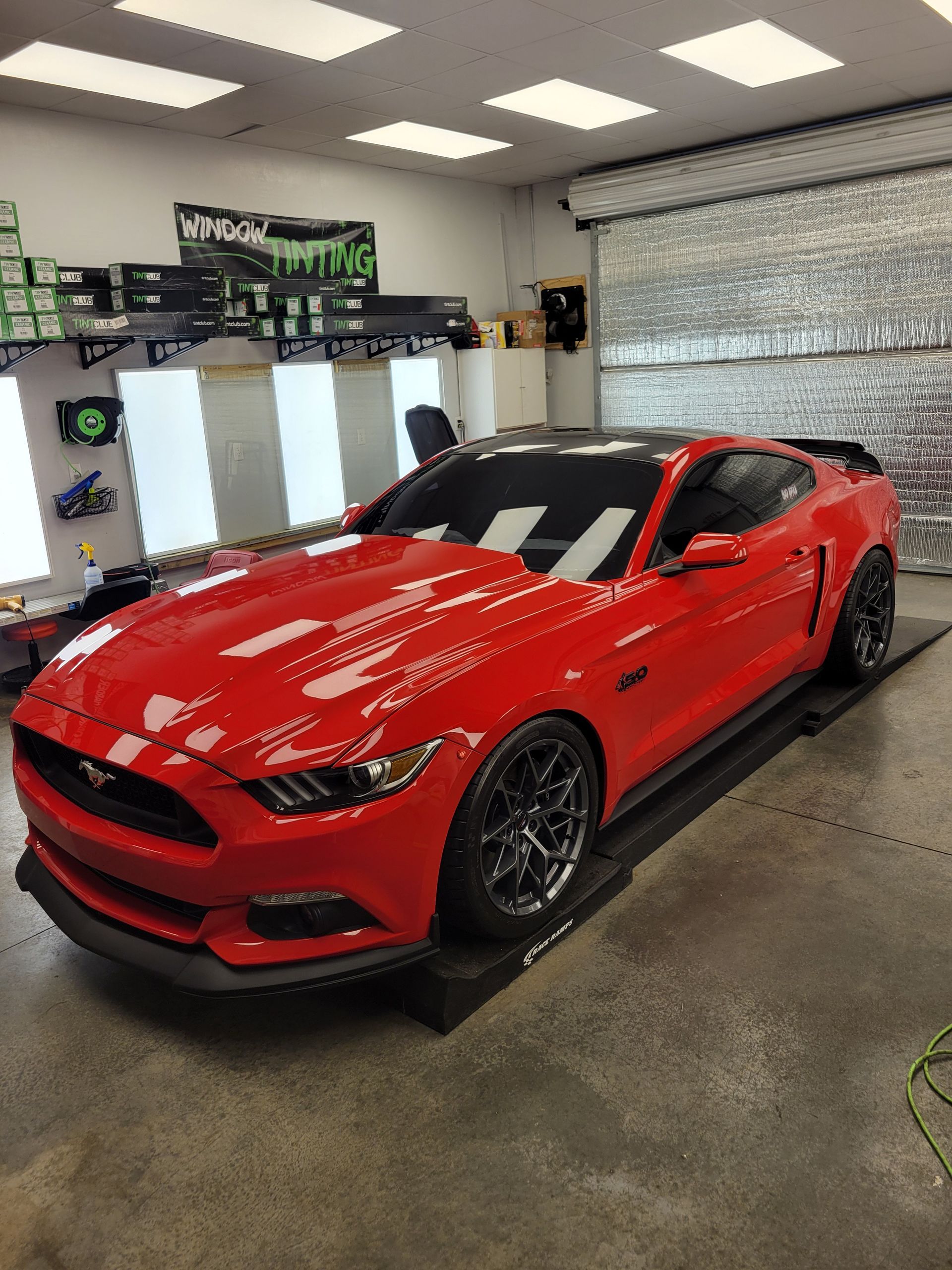 Red sports car in a bright garage, shown from the front-left side.
