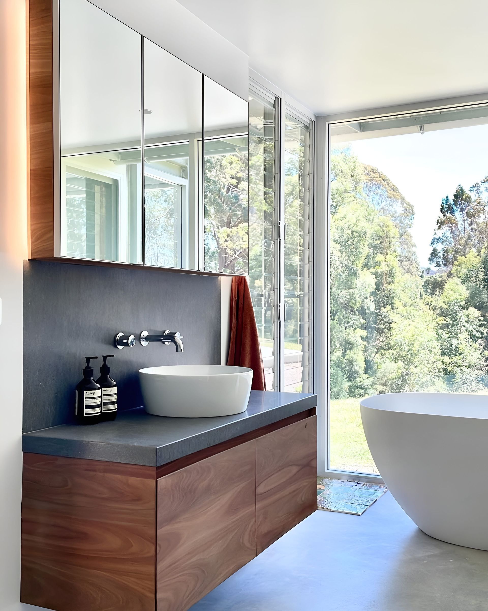 Modern bathroom with wooden vanity, vessel sink, and large window overlooking trees — BSpoke Cabinet Making & Joinery in Unanderra, NSW