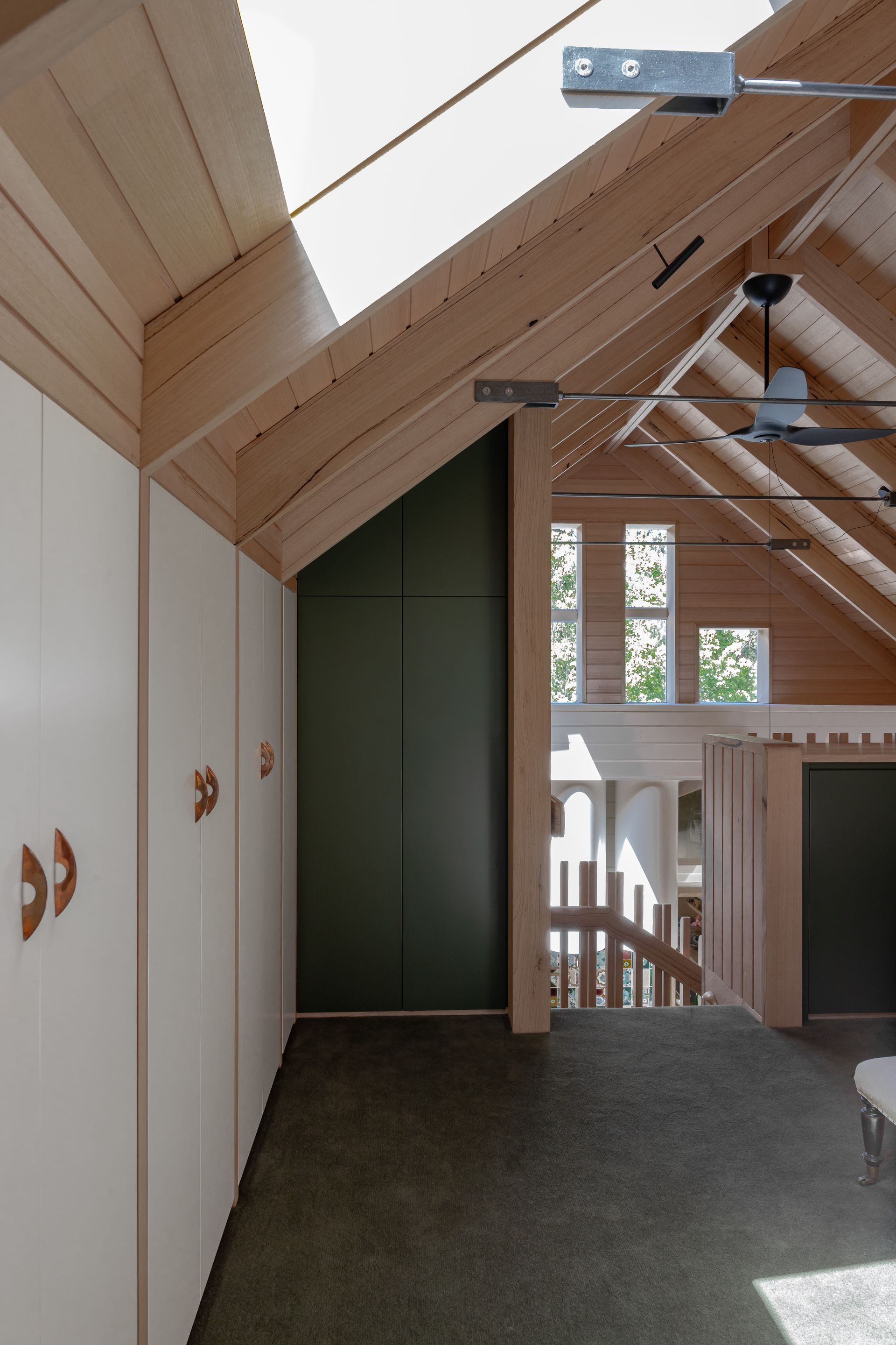Wooden-beamed attic interior with white closets, dark green wall, and a staircase leading to sunlight-filled windows — BSpoke Cabinet Making & Joinery in Unanderra, NSW