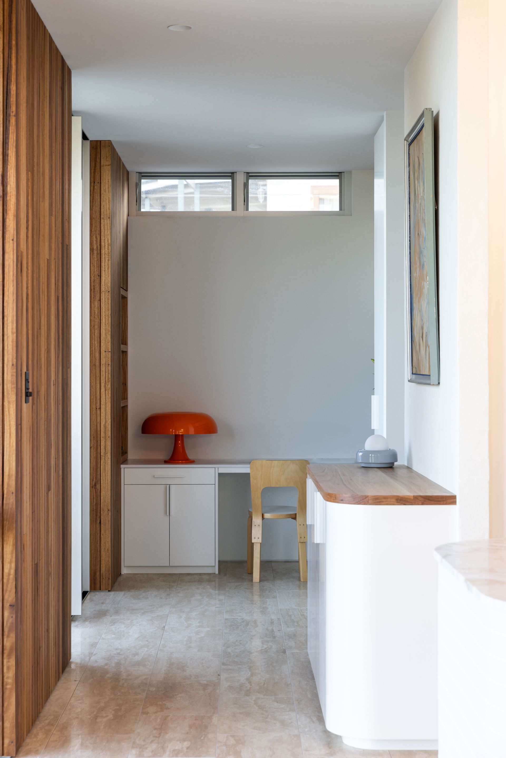 Hallway with built-in desk, orange lamp, wooden door, and white cabinets — BSpoke Cabinet Making & Joinery in Unanderra, NSW
