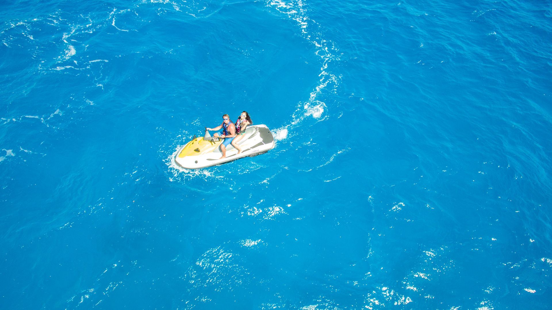 Two people Jet skiing in open blue water