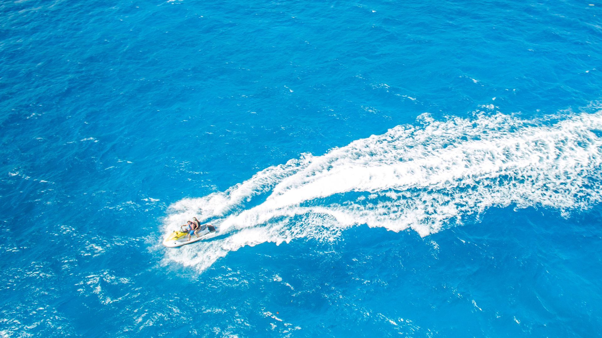 Two people on a jet ski in bright blue ocean water