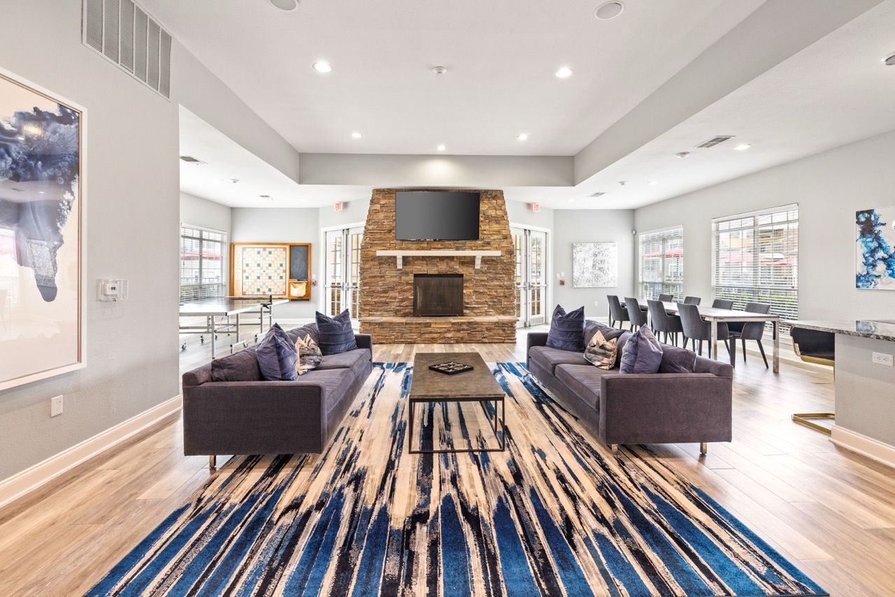 Spacious community lounge with a stone fireplace, mounted TV, and plush seating.