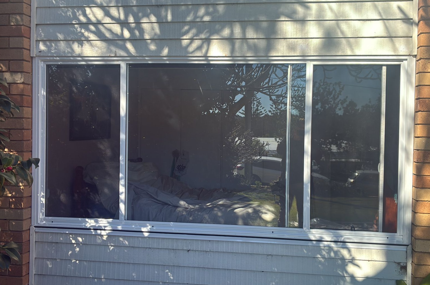Large white-framed window on a house exterior with curtains and reflections of trees and sky — Kracken Windows and Doors In Terrey Hills, NSW