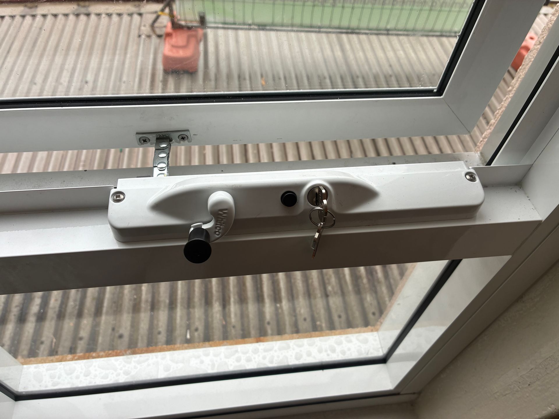 White window handle and lock on a tilted window overlooking a rooftop and railing — Kracken Windows and Doors In Terrey Hills, NSW