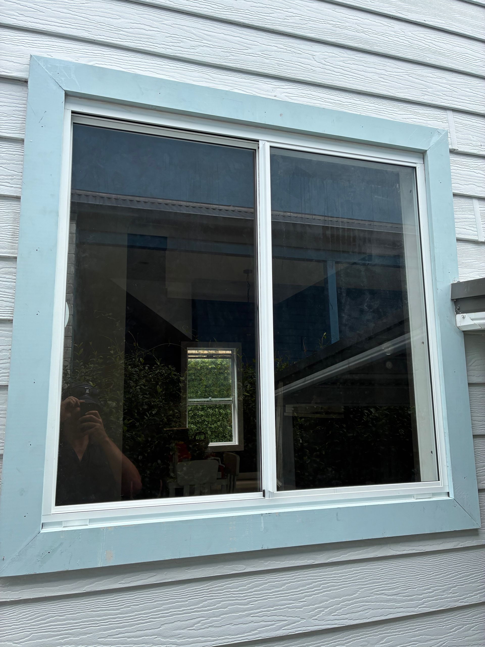 White-framed window with a blue exterior wall and a reflection of the room inside — Kracken Windows and Doors In Terrey Hills, NSW
