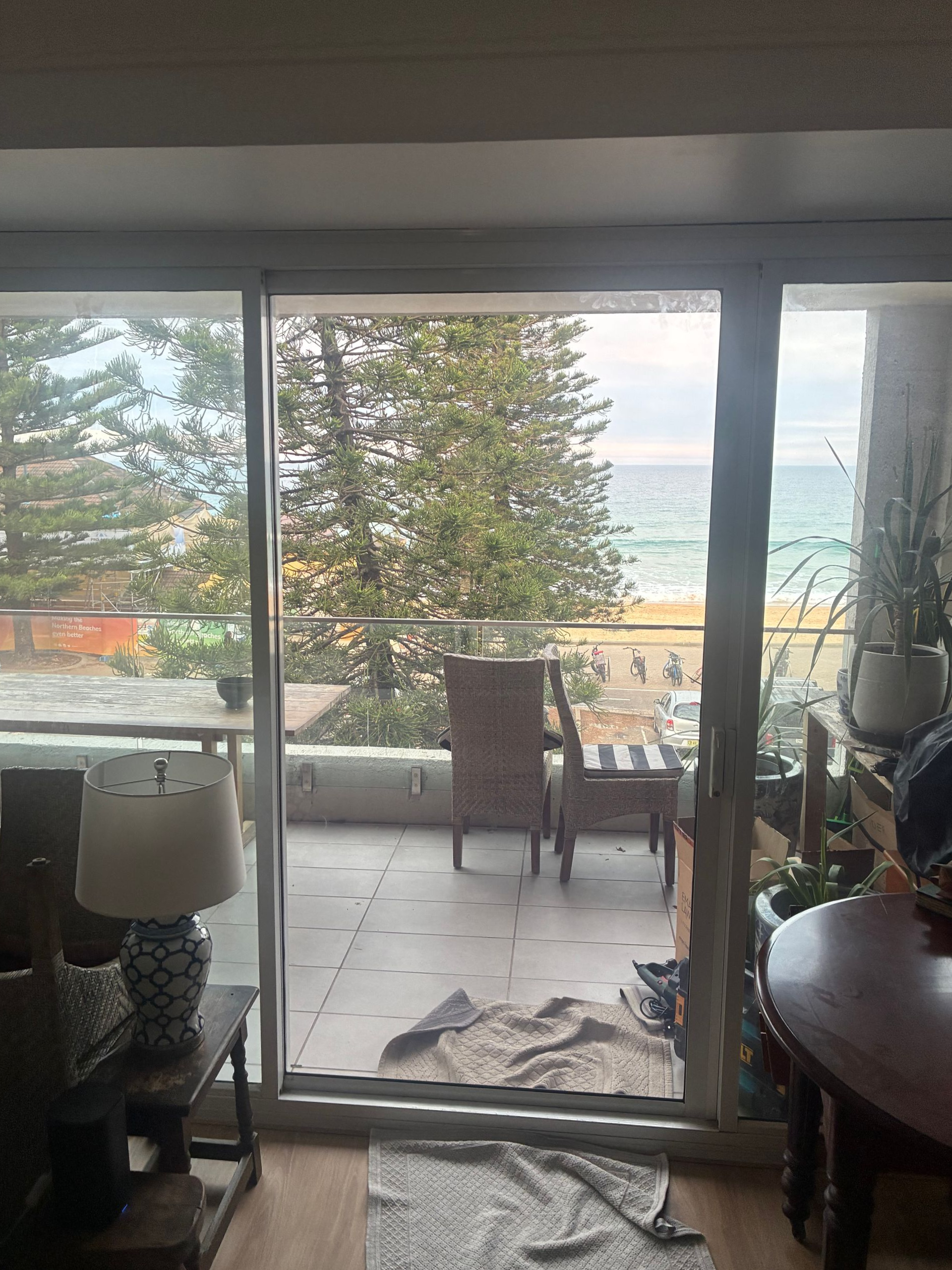 Sliding glass doors open to a patio with chairs and trees outside. — Kracken Windows and Doors In Terrey Hills, NSW