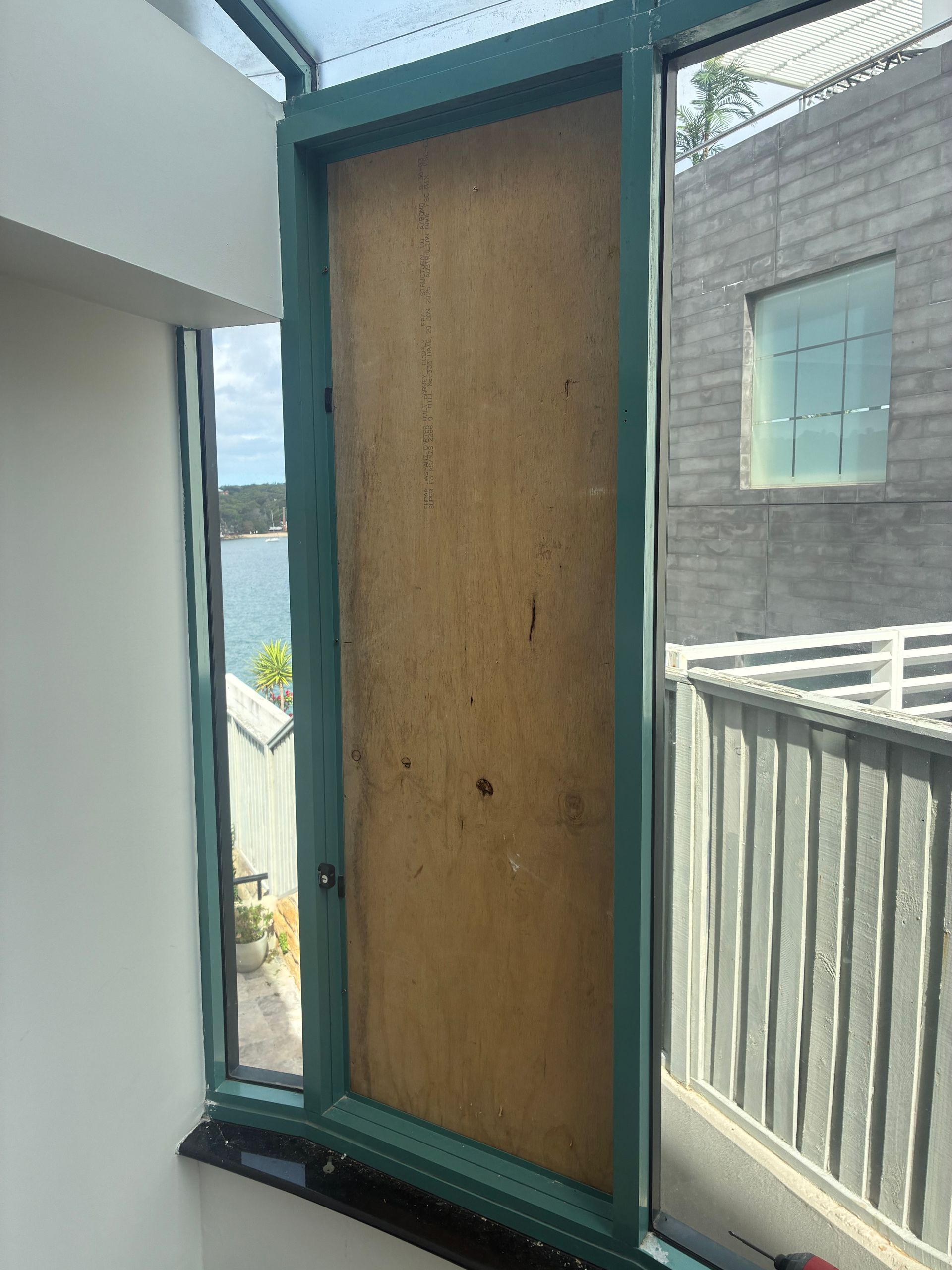 Boarded-up doorway with teal trim opening to a balcony beside a brick building. — Kracken Windows and Doors In Terrey Hills, NSW