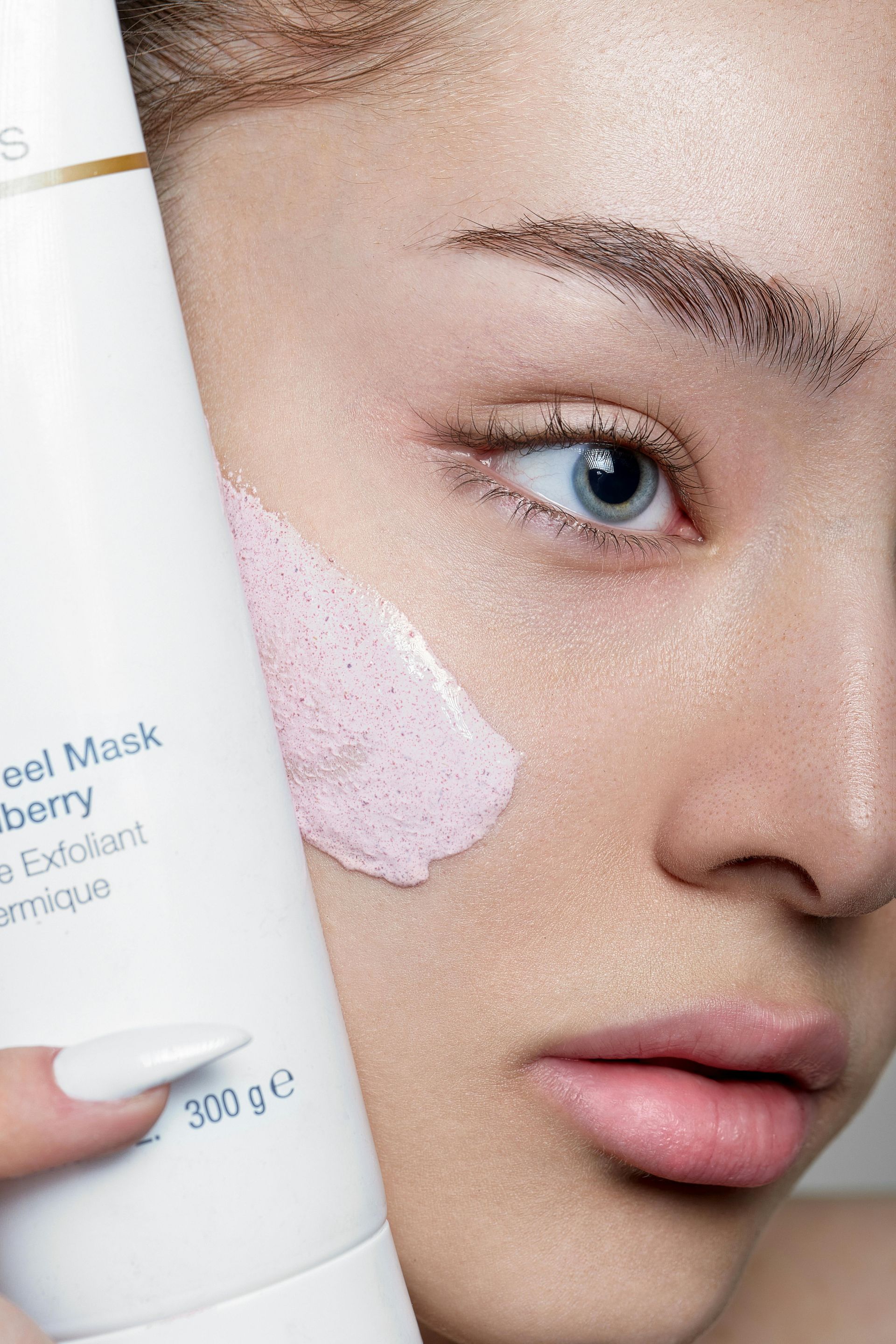 Une femme tient une bouteille de masque peeling sur son visage.