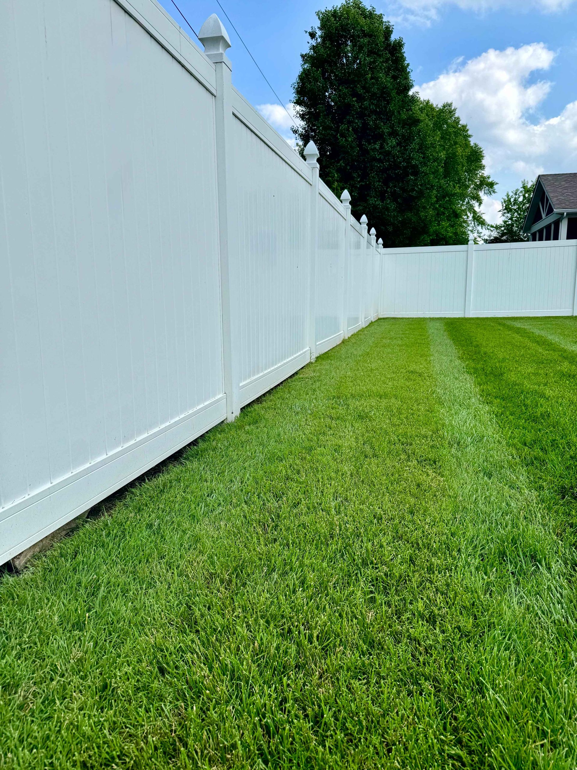 A white fence surrounds a lush green lawn.