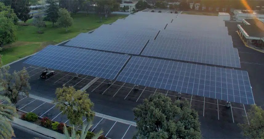 Aerial view of a large parking lot covered with solar panel canopies at sunset