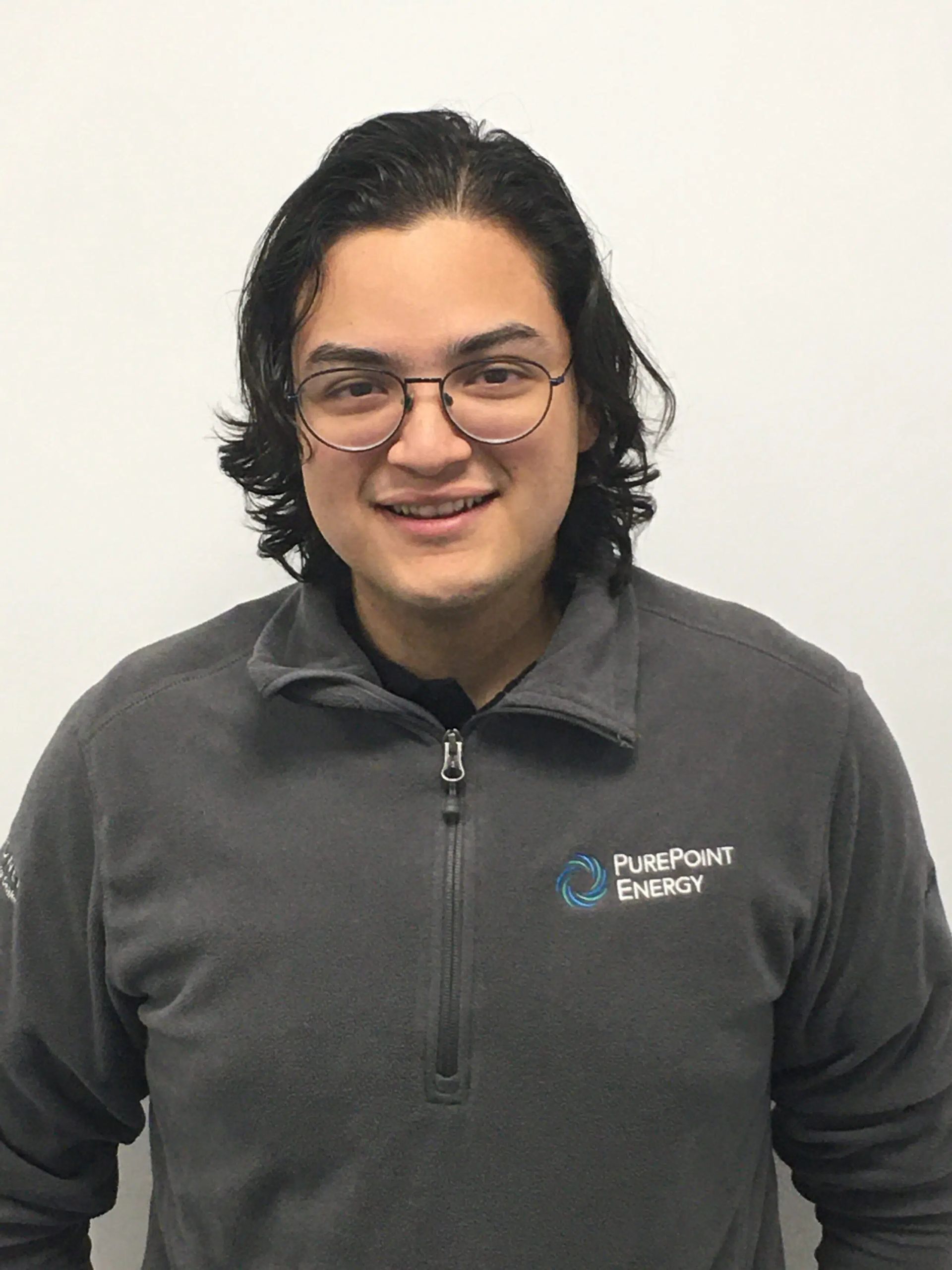 Smiling person with glasses in a gray quarter-zip pullover against a plain white background
