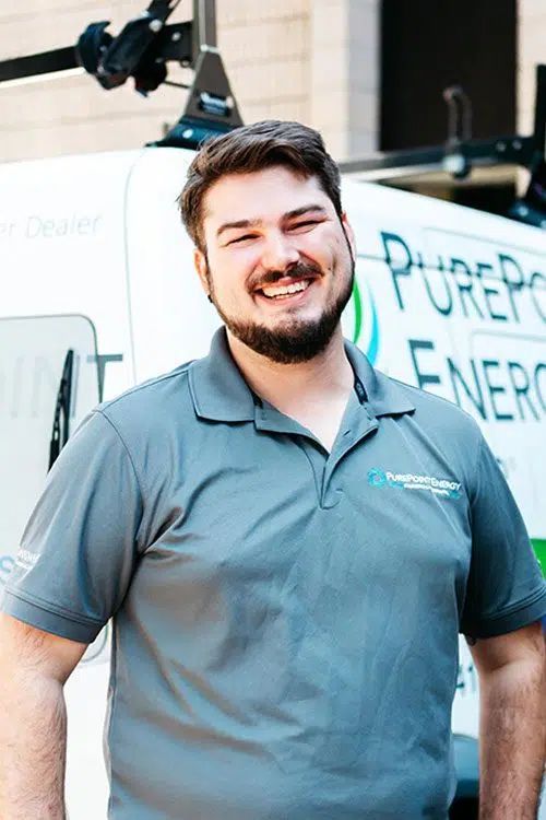 Smiling man in a gray polo stands in front of a PurePoint Energy service truck.