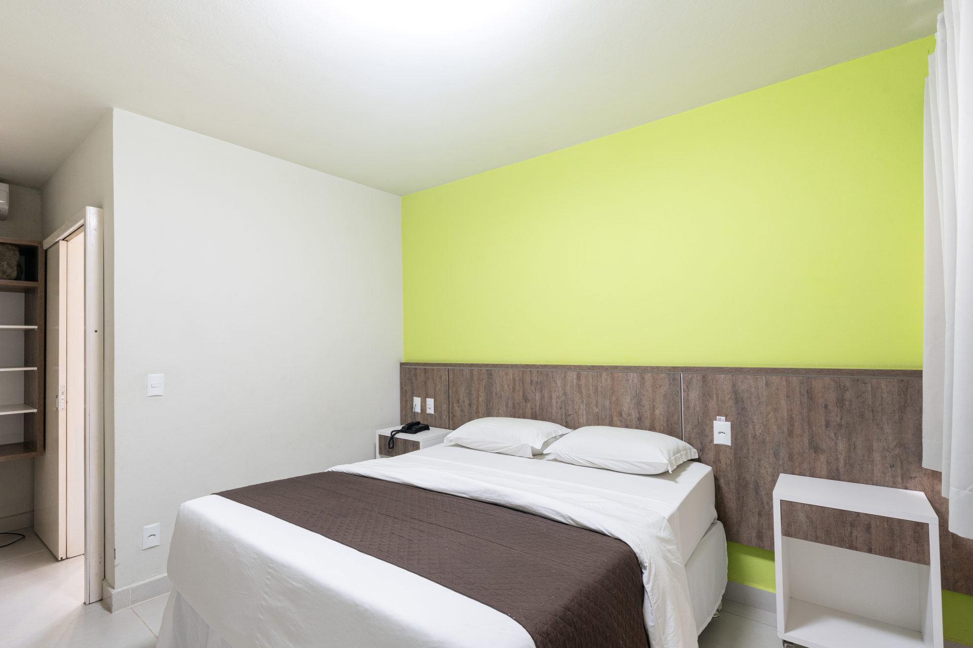 Um quarto de hotel com uma cama grande e uma parede verde