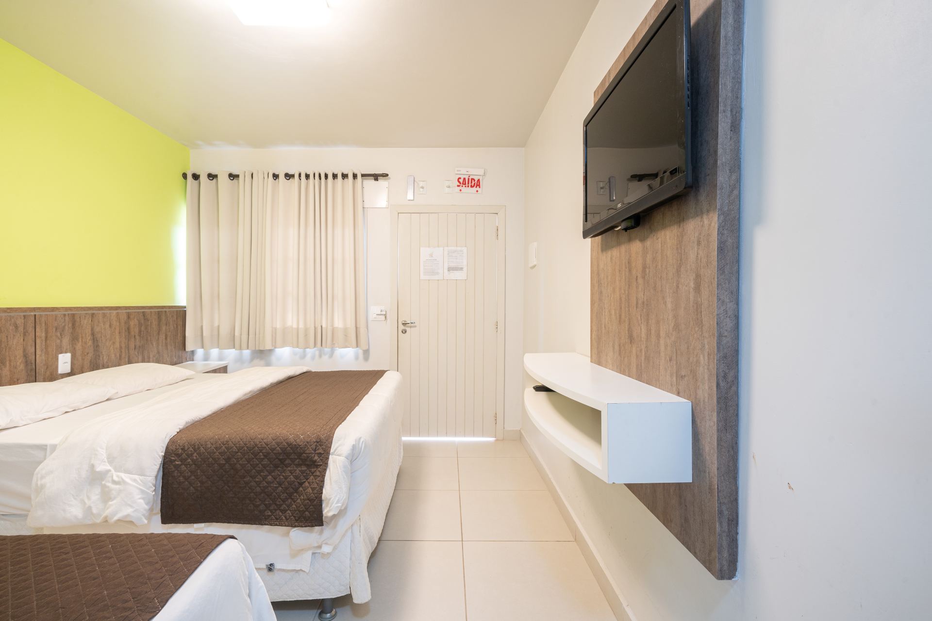 Um quarto de hotel com duas camas e uma TV de tela plana na parede.