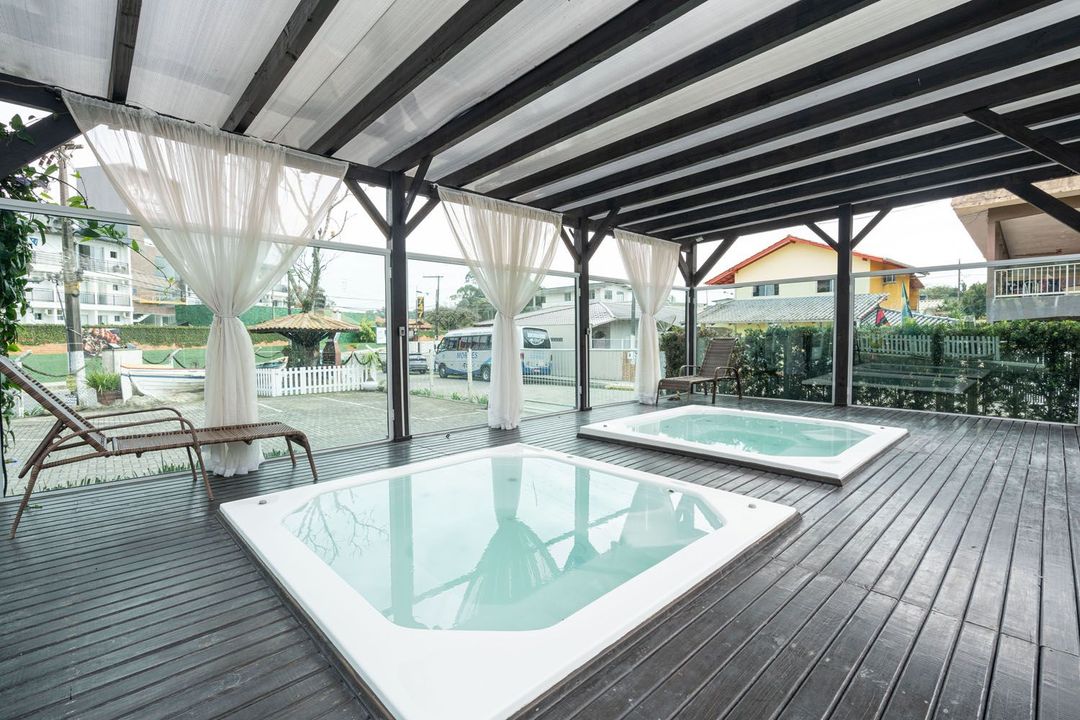 Duas banheiras de hidromassagem estão sobre um deck de madeira sob um dossel.