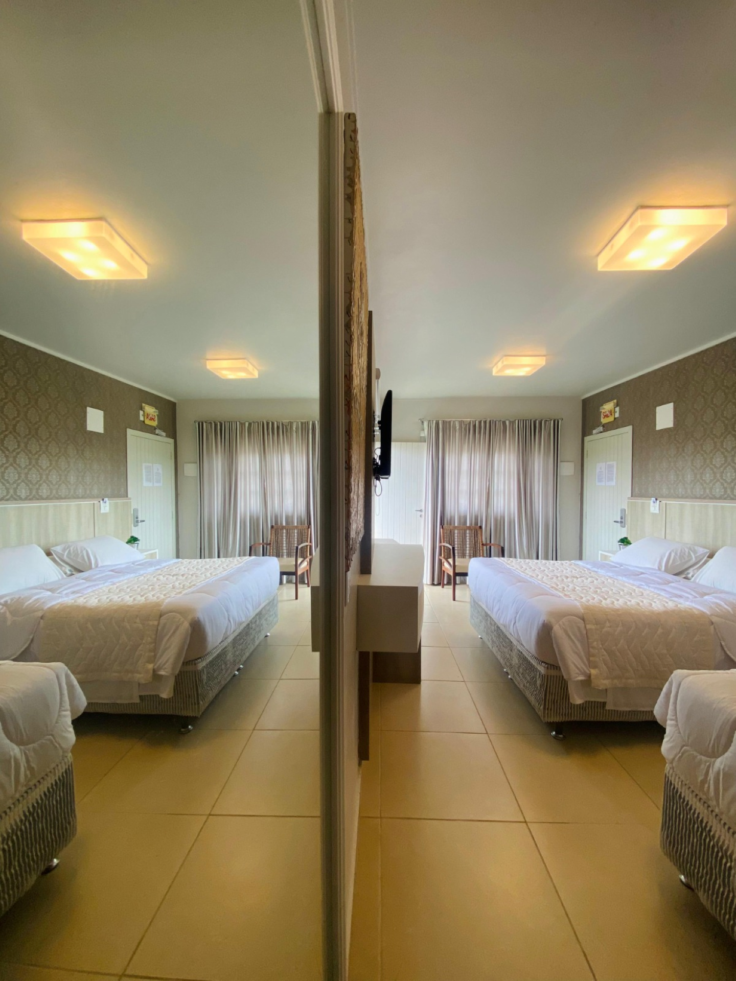 Um quarto de hotel com duas camas e uma televisão na parede.