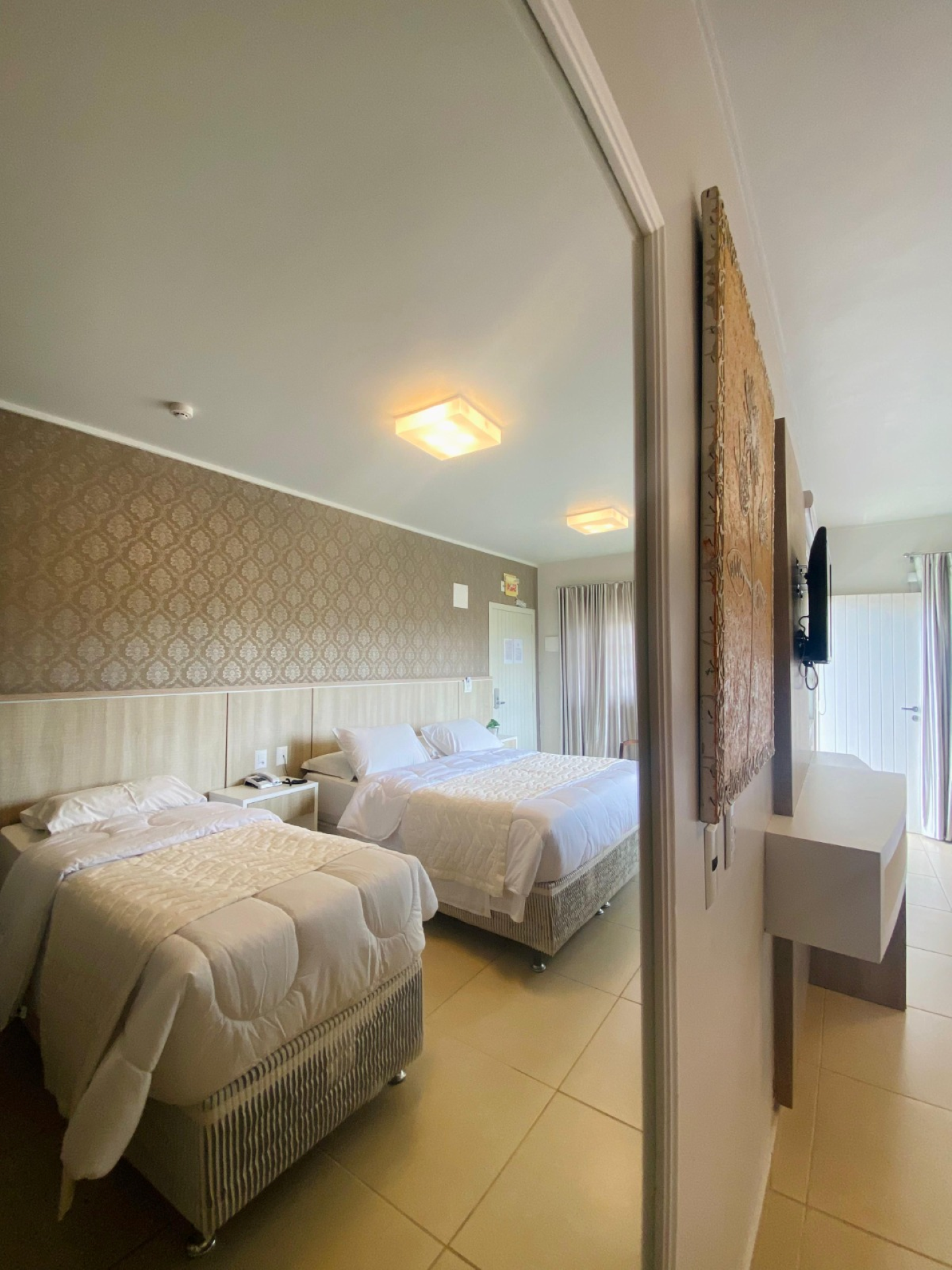 Um quarto de hotel com duas camas e uma televisão na parede.