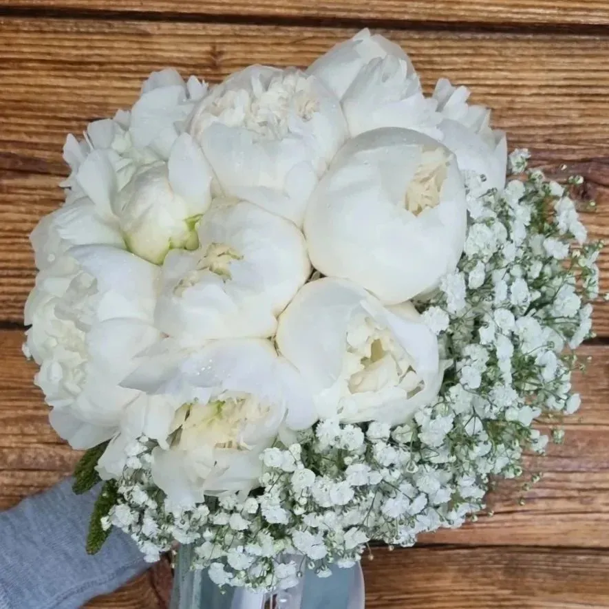 Bouquet di fiori bianchi con rose e gypsophila su sfondo di legno.