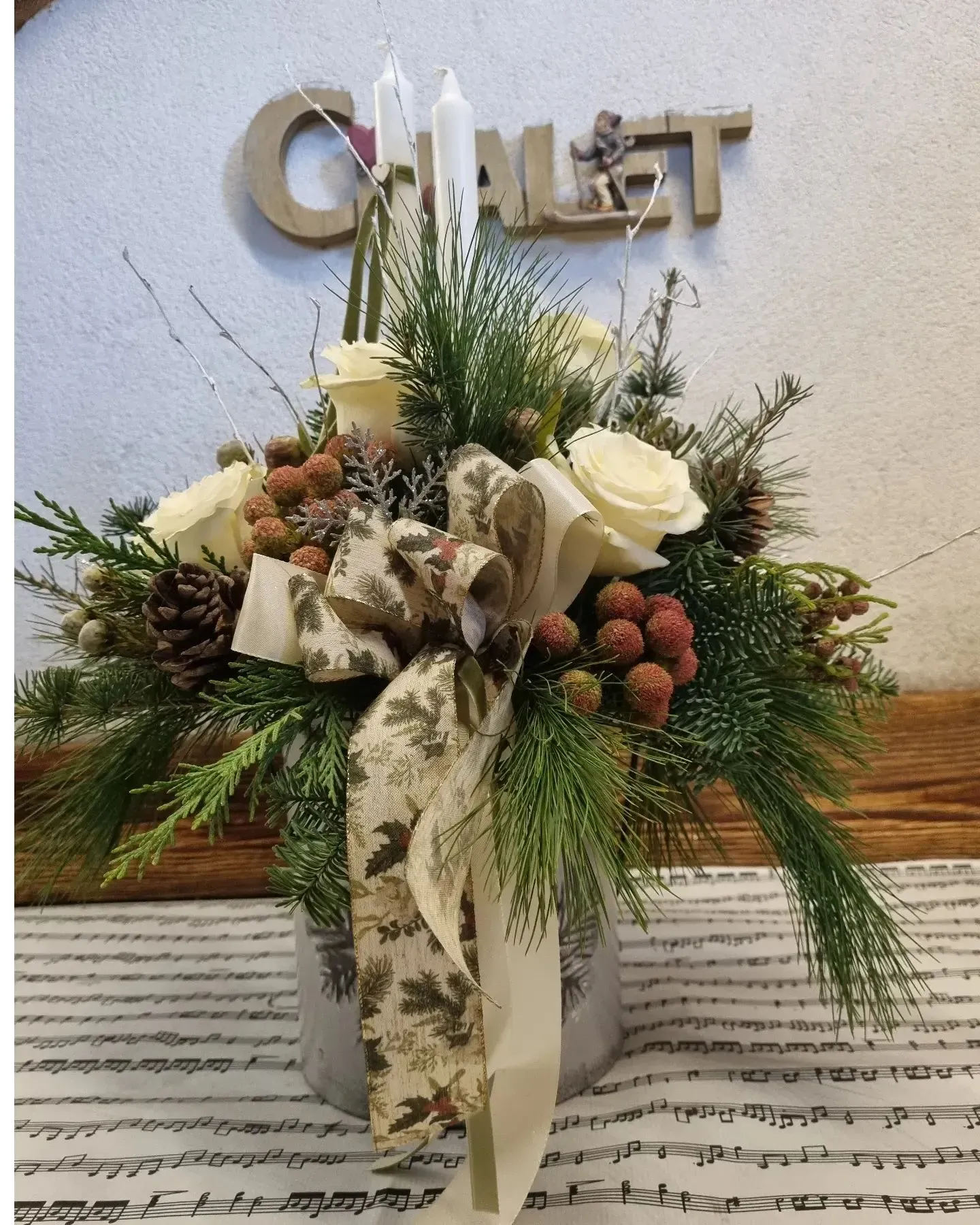 Composizione floreale con rose bianche, verde e spighe di grano su un tavolo sotto un'insegna con la scritta 