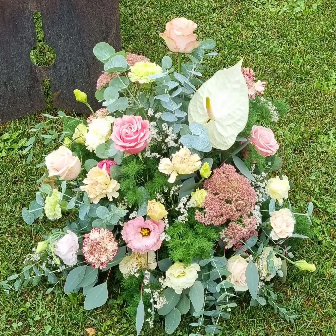 Un assortimento di fiori dai colori pastello disposti in un lussureggiante bouquet da giardino su un prato verde.