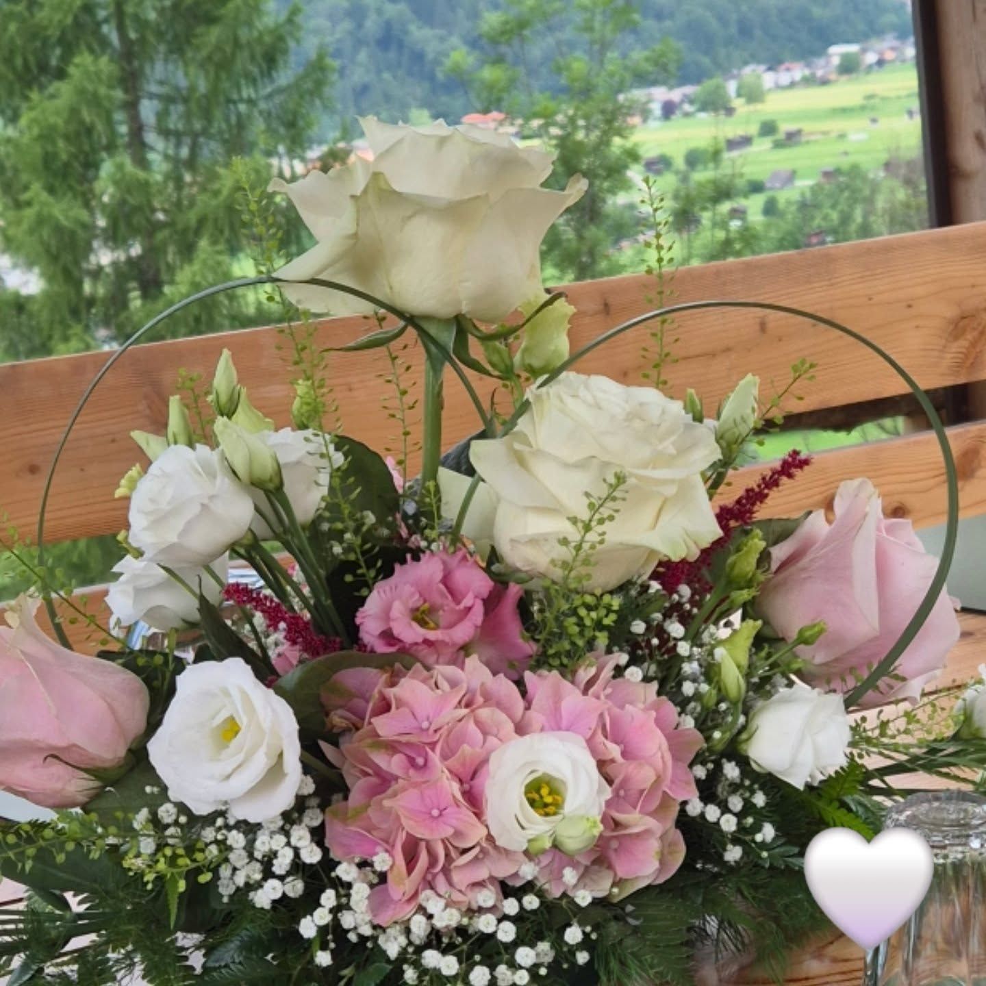 Bouquet di rose bianche e rosa in una scatola di legno con uno splendido paesaggio verde sullo sfondo.