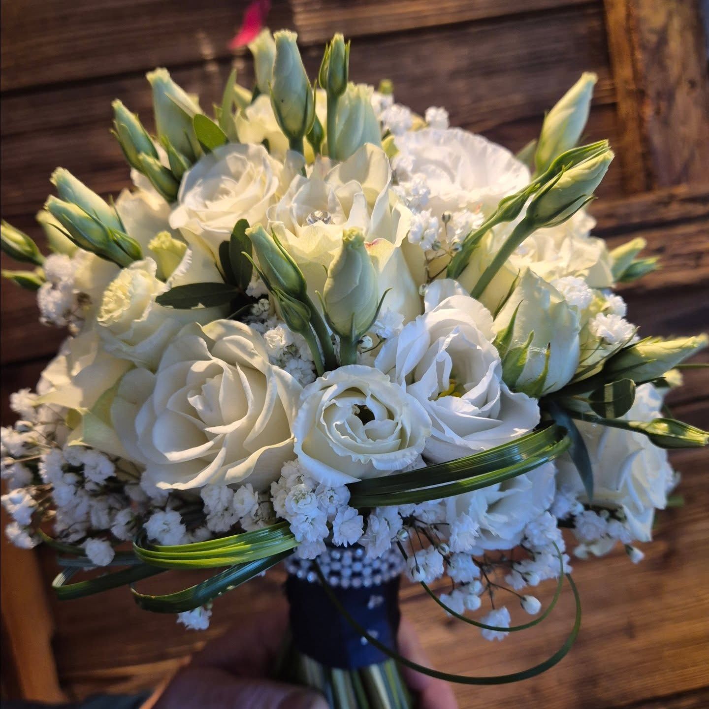 Bouquet di rose bianche e gigli con gypsophila, avvolto in un nastro blu.