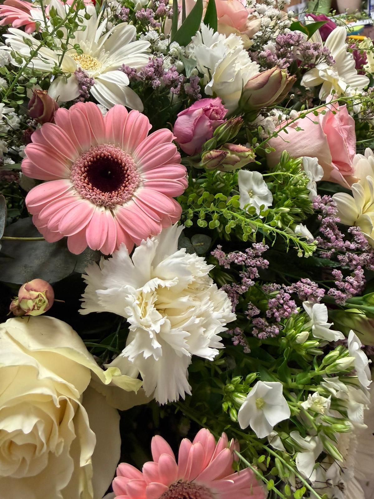 Un assortimento di fiori rosa e bianchi, tra cui rose e margherite, in un lussureggiante bouquet.