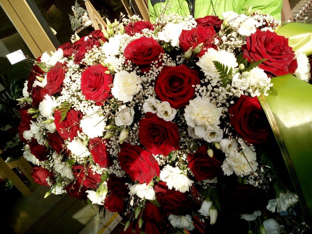 Bouquet di rose rosse e bianche con verde, disposto a formare una ghirlanda floreale.