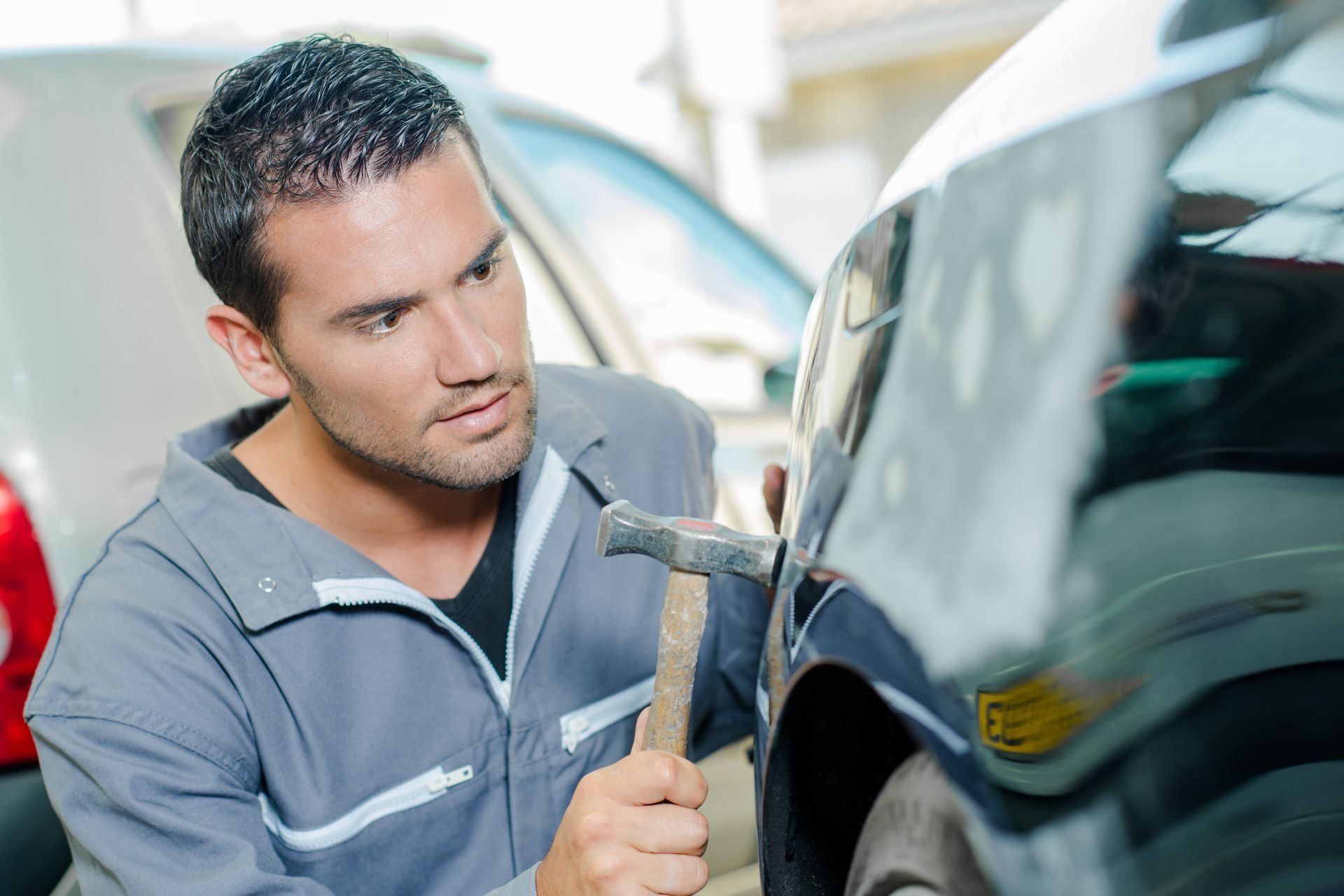 Mechanic panel beating a car.
