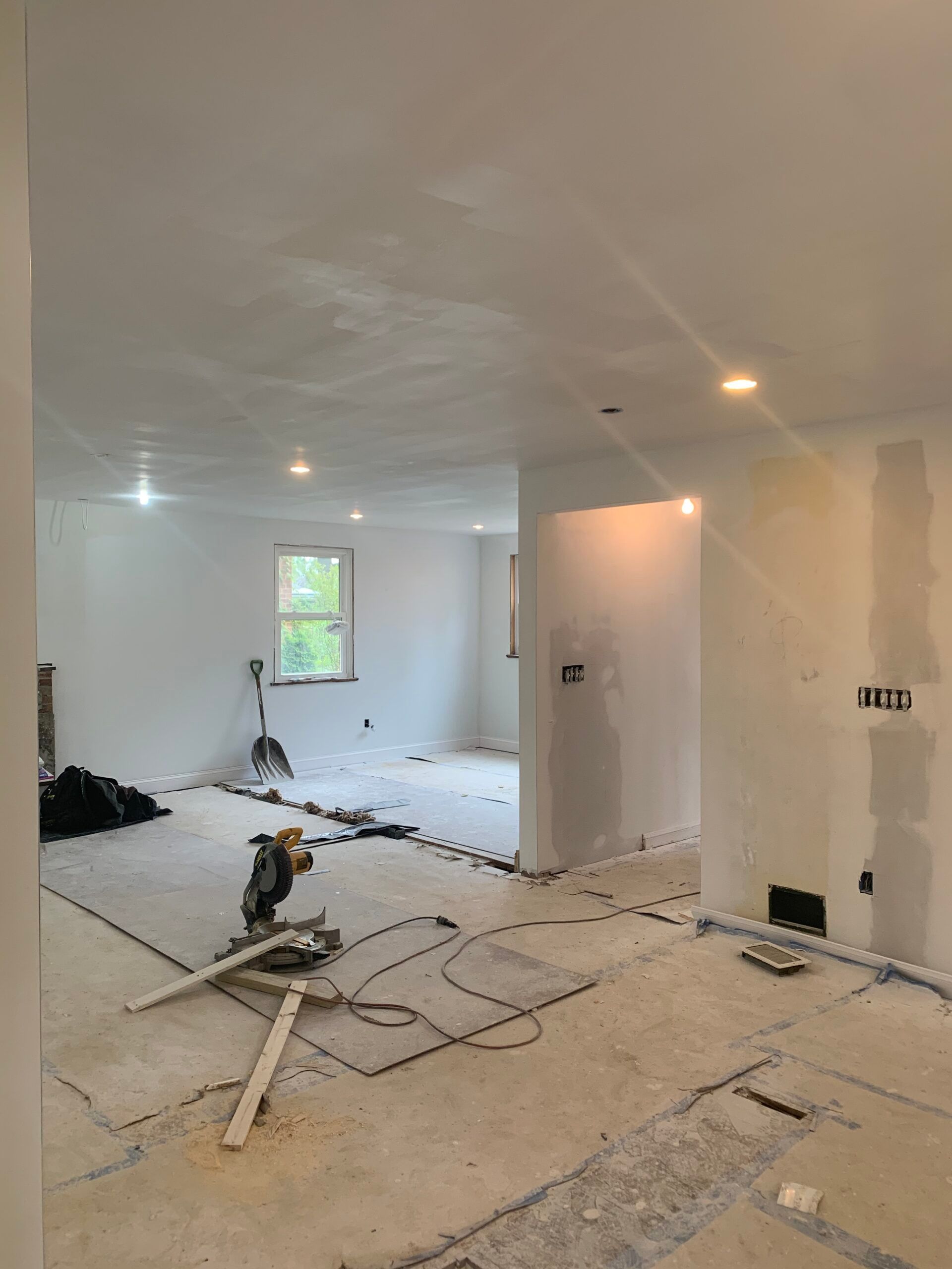 Interior room under renovation with drywall, exposed flooring, and construction tools.