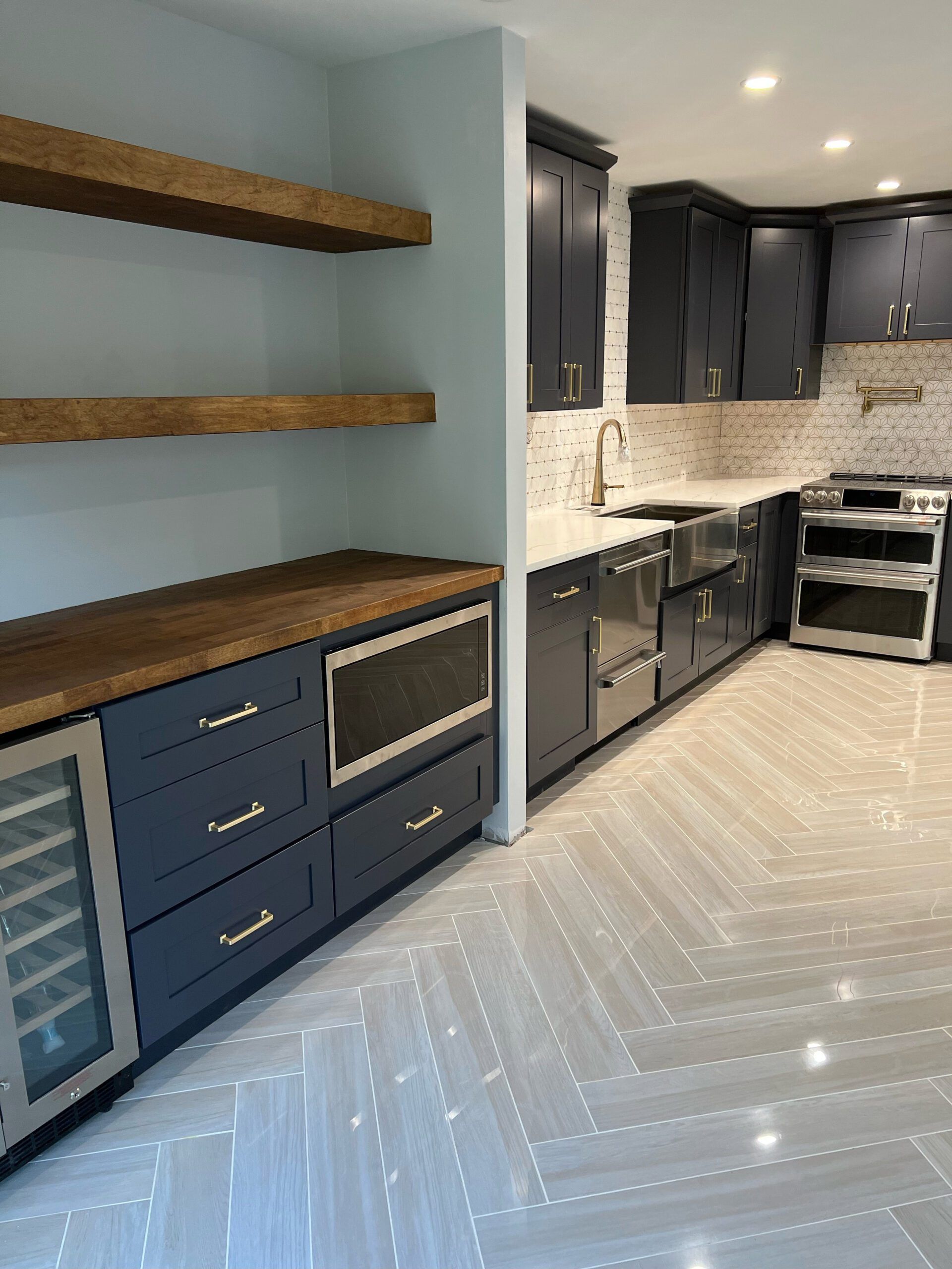 Navy blue kitchen with wood shelves and countertops, stainless steel appliances, and light tile floor.