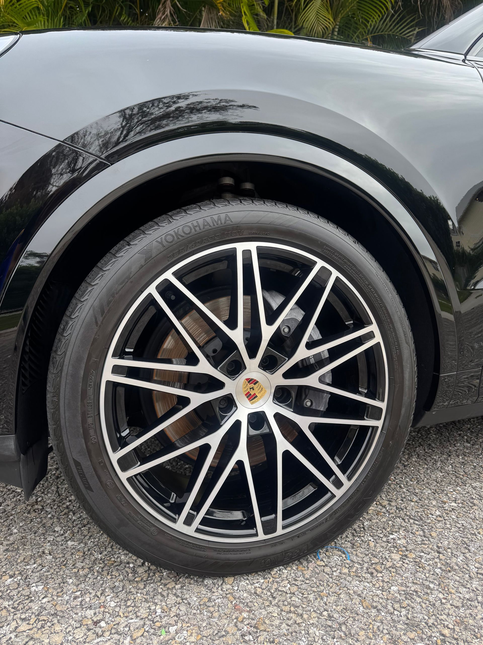 Black car wheel with multi-spoke alloy rim and tire, close-up on a wet road