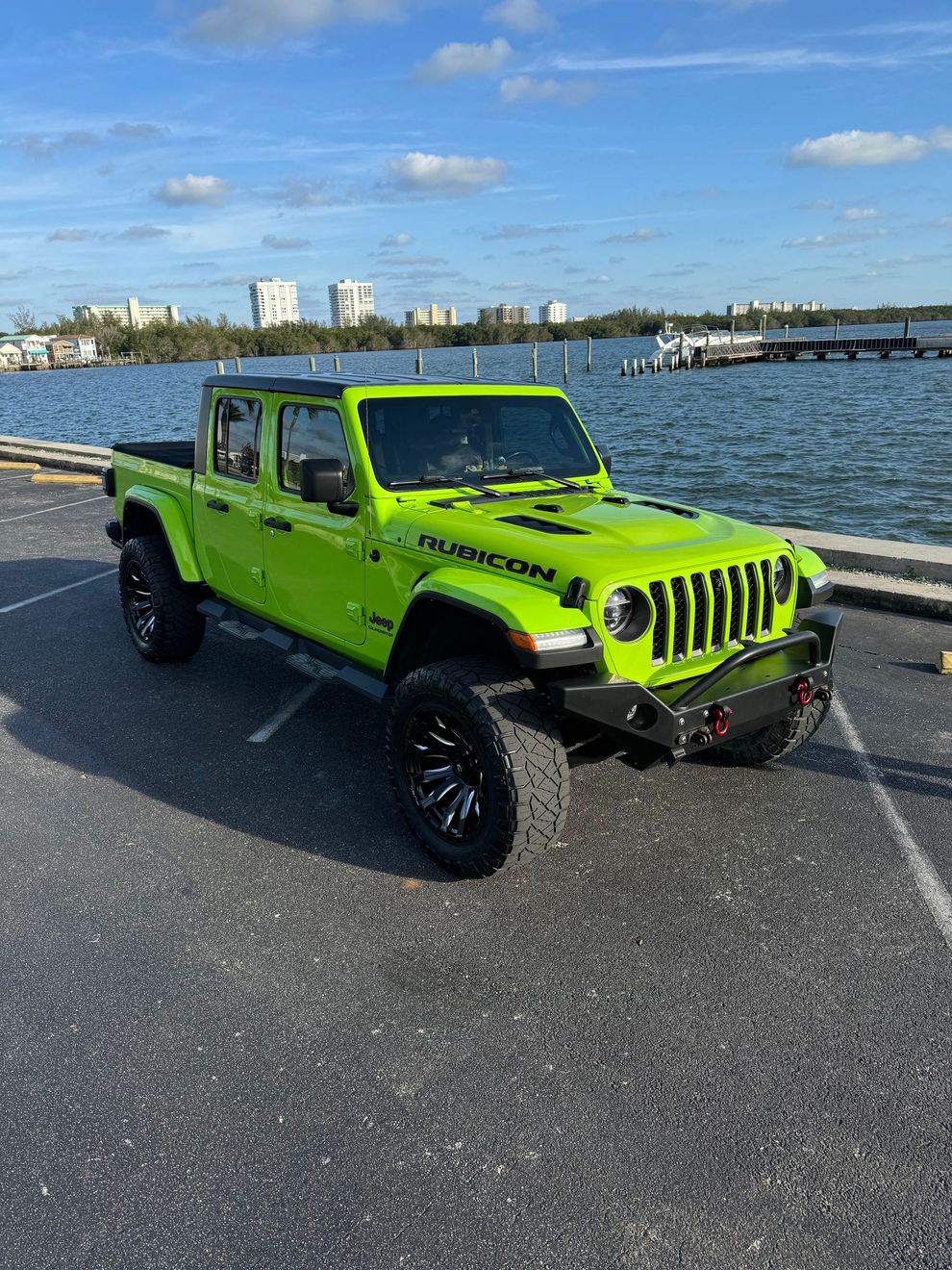 Neon green Jeep Gladiator parked by the waterfront on a sunny day