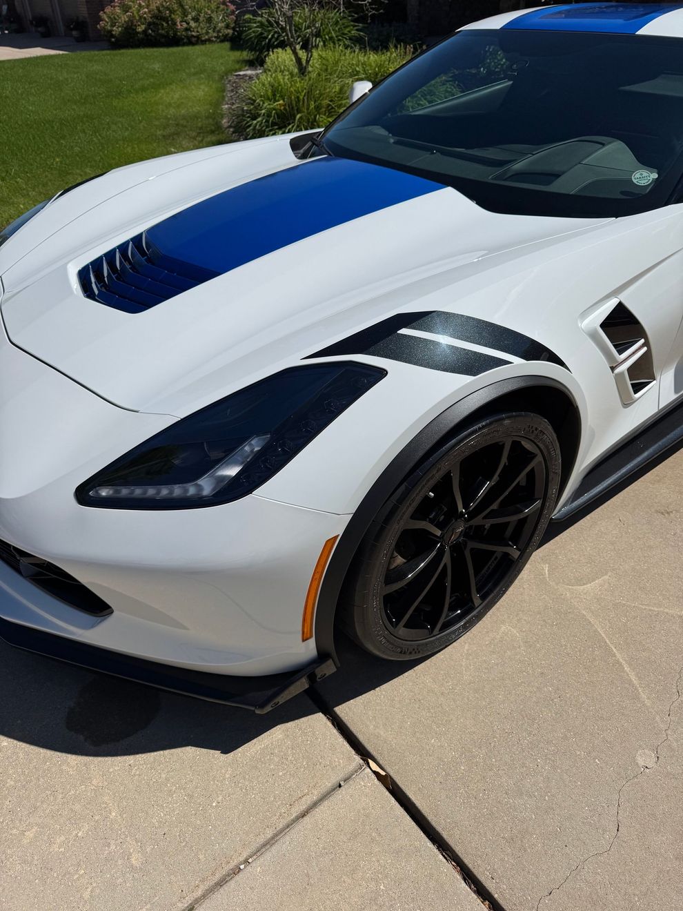 White sports car with blue hood accent parked on a driveway